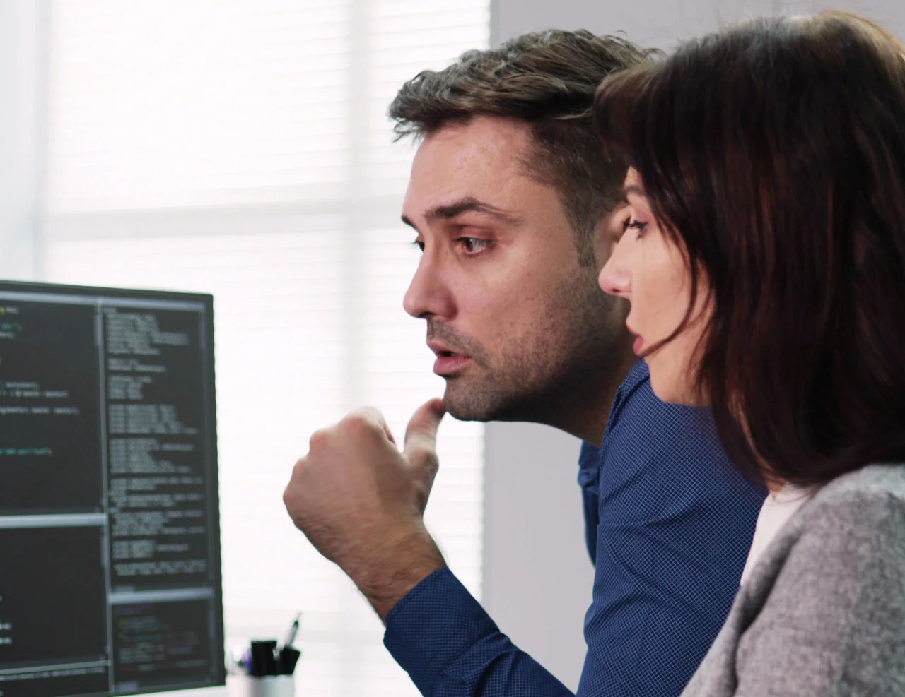 Two developers discussing source code displayed on a computer monitor