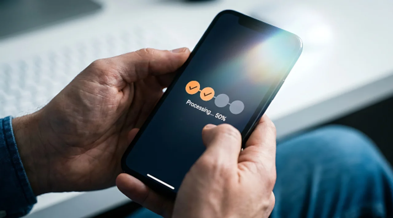 Person holding a smartphone displaying a processing progress indicator