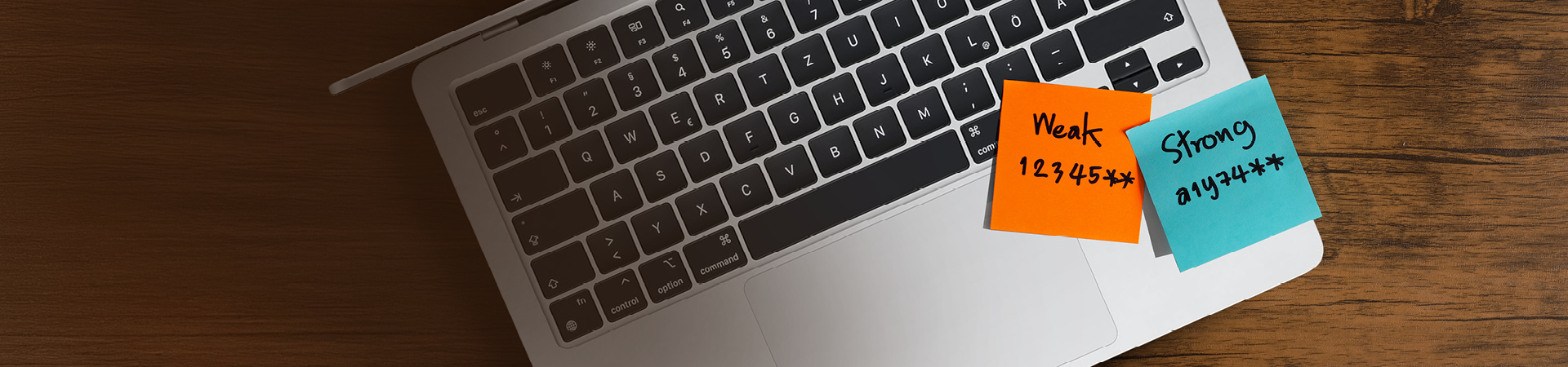 Zwei Haftnotizen kleben auf einer Laptop-Tastatur, eine mit einem schwachen Passwort und eine mit einem starken Passwort