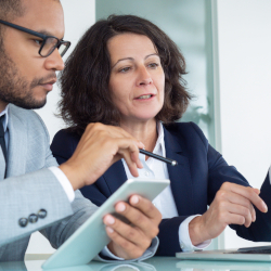 Businesswoman discussing information on a tablet with a male colleague in an office