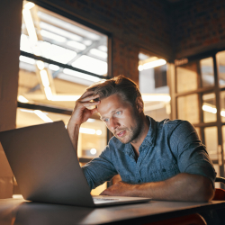 Stressed man working on a laptop at an office desk