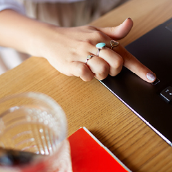 Woman’s hand with extended index finger using a fingerprint sensor to unlock a laptop