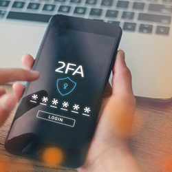 Eine Person hält ein Smartphone in der Hand und führt eine Zwei-Faktor-Authentifizierung durch