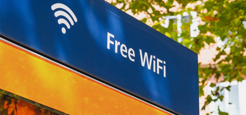 A building wall with a shop sign reading “Free WiFi,” with tree branches in the background